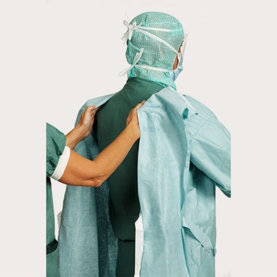 Chirurg en omloopverpleegkundige tonen stap 4 van het aantrekken van een operatiejas