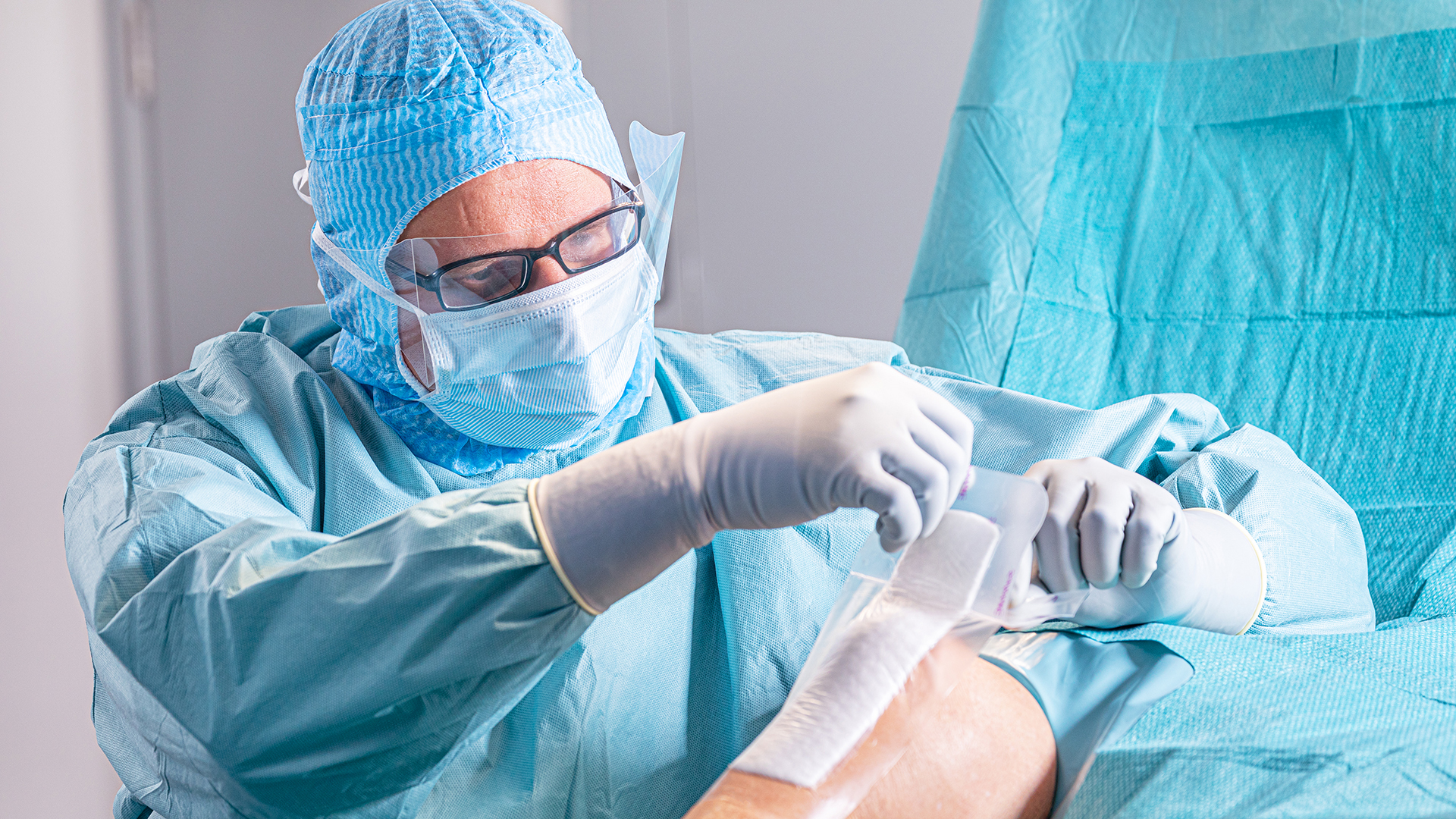 Arts gekleed in operatiekleding die tijdens een operatie een wondverband aanbrengt