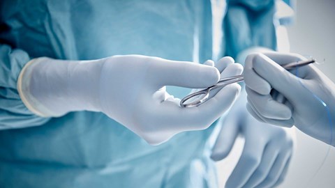 Chirurgen met operatiehandschoenen die een instrument vasthouden